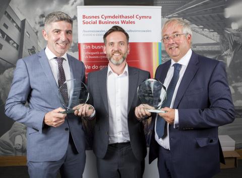 Three men smiling with awards