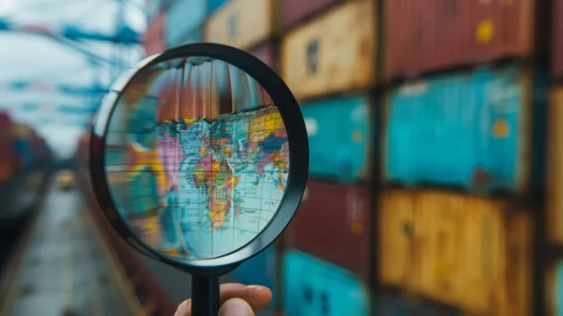 Shipping containers and map of the world viewed through a magnifying glass 