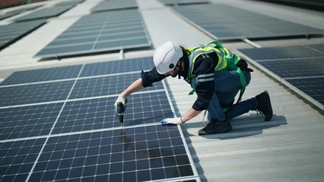 Engineer fixing solar panels to roof 