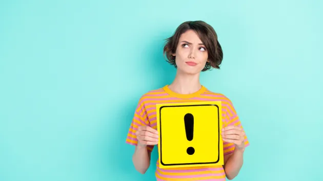 Person holding a sign with an exclamation mark.