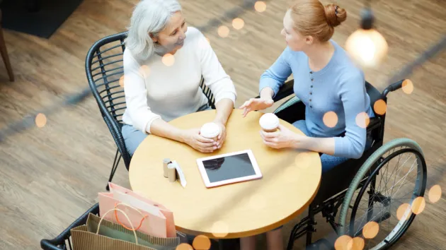 Wheelchair user working in an office talking to a colleague