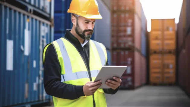 person using a digital device checking shipping containers 