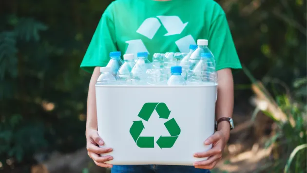 Recycling - person carrying a recycling carton full of plastic bottles 