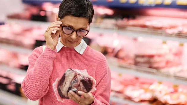 Person reading a label on packaged meat 