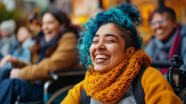 Wheelchair user - woman wearing a yellow scarf and hair dyed blue 