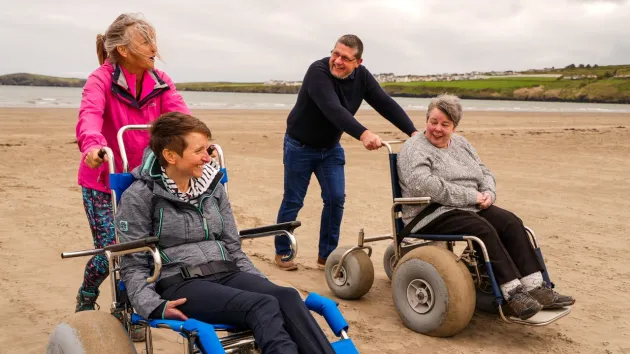 People on a beach, people using beach wheelchairs 