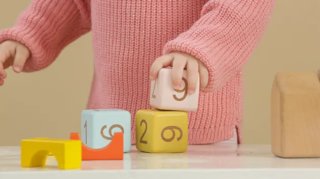 child stacking wooden building blocks 