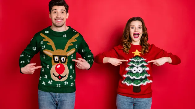 One person wearing a jumper with a Reindeer, another person wearing jumper with a Christmas tree