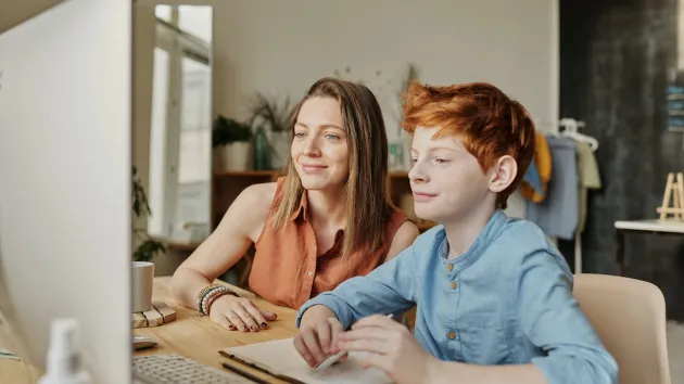 photo of Woman and Boy Smiling While Watching Through Imac