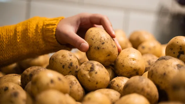 someone picking potatoes at a supermarket 