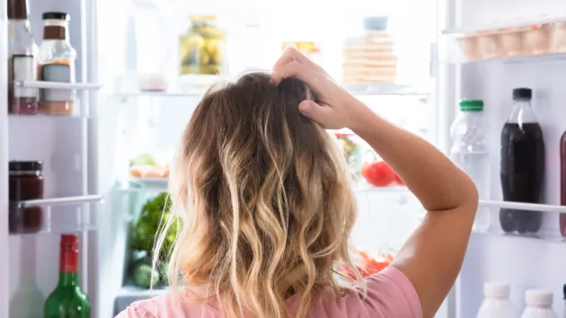 Person looking puzzled at an open fridge 