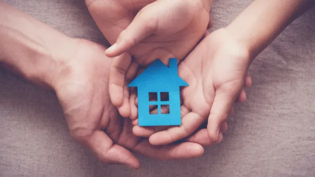 Adult and child hands holding paper house