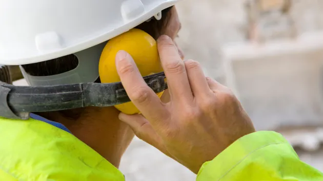 Construction worker wearing protective hard hat and ear defenders