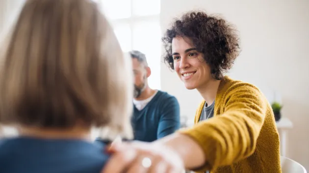 Men and women sitting in a circle during group therapy, supporting each other.