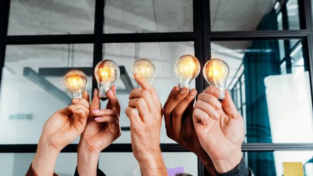 Teamwork concept with business people holding lightbulbs