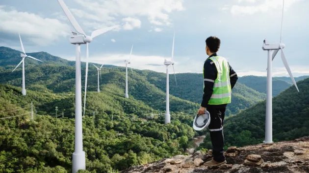 Young maintenance engineer man working in wind turbine on the mountain,power generation saving and using renewable energy concept.