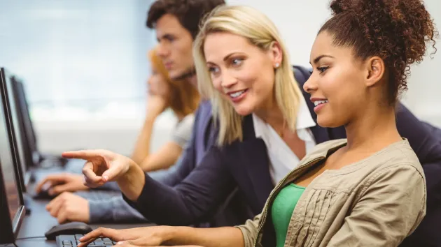  teacher talking to her student in computer class 