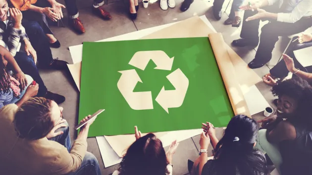 Colleagues gathered around a recycling poster 