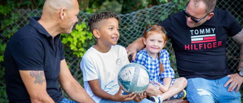 Two men sat down looking at two children between them