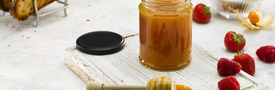 Jar of Welsh Heather Honey on a white board surrounded by toast and berries