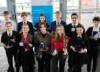A group of Students who have won their awards are stood together in Front of a banner 