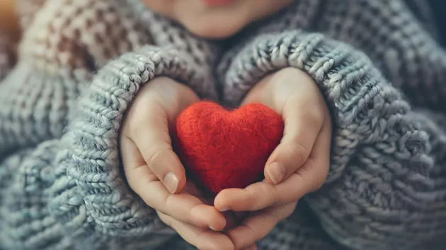 Person holding a red love heart made of wool 