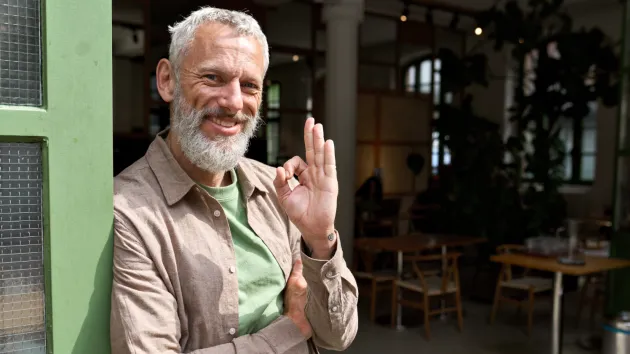 happy older business owner stood outside premises 