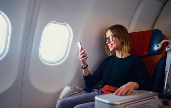 Traveling and technology. Flying, woman using smartphone while sitting in airplane.