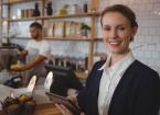 Portrait of smiling female owner using digital tablet with waiter working in cafe