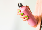 Young woman holding pink reusable stainless thermo water bottle