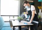 Male worker cleaning table with disinfectant in restaurant during coronavirus outbreak