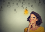 Thinking woman in glasses looking up with light idea bulb above head isolated on grey wall background