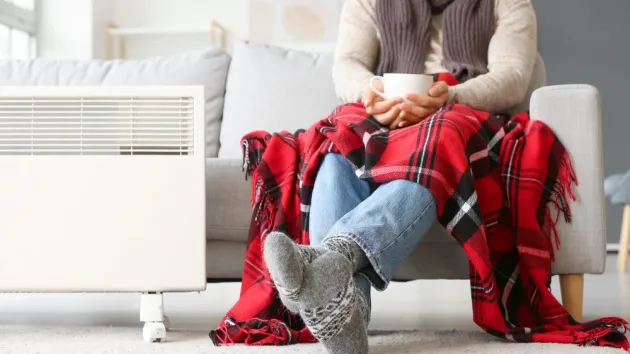 Young man in warm clothes and with cup of tea at home. Concept of heating season.