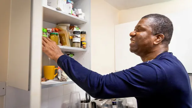 Person looking in a kitchen cupboard at food products 