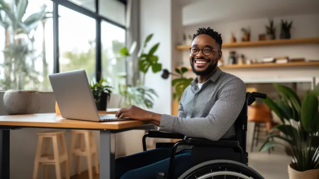 Wheelchair user working in an office talking to a colleague