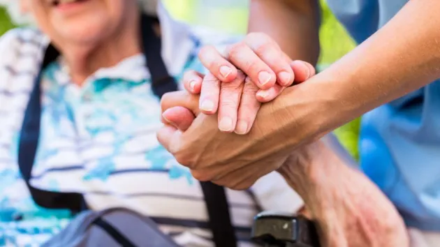 carer holding the hand of a patient