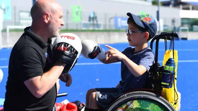 child wheelchair user boxing with an instructor 
