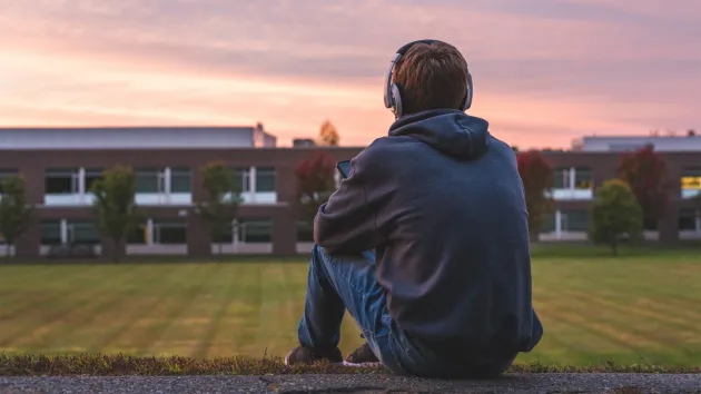 teenager sitting in field 