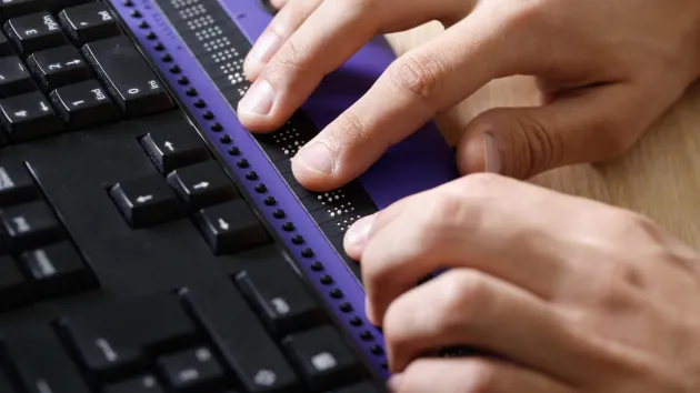 person using braille and computer