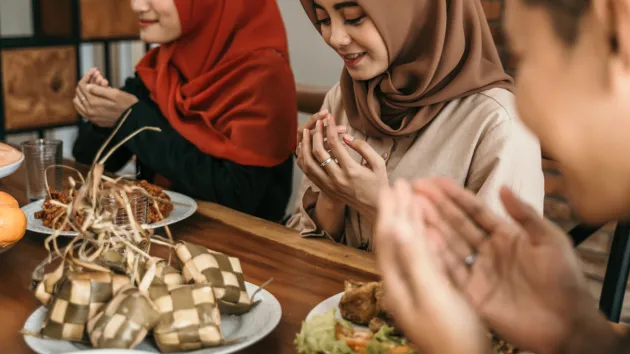 Muslim women and men praying before eating