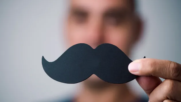 Man holding a face paper moustache 