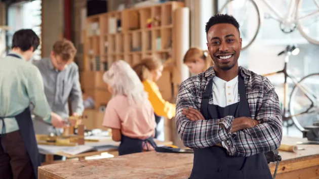 Small business owner smiling with colleagues in the background