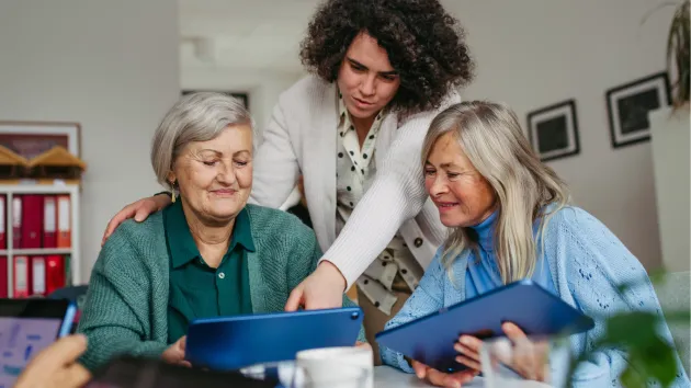 Volunteer teaching mature people how to use a digital device 