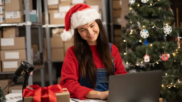 Warehouse worker wearing a Santa hat and packing parcels