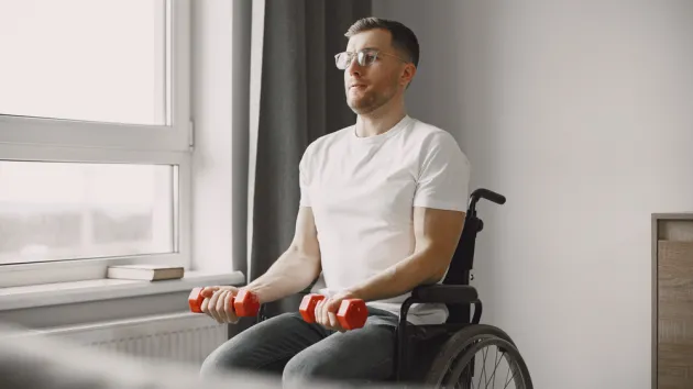 Young man in wheel-chair doing exercises indoors
