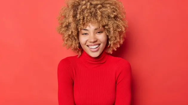 happy young woman smiles broadly wears a red sweater 