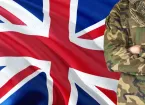 Crossed arms British soldier with national waving flag on background - United Kingdom Military theme.