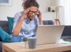 stressed female looking at a laptop, victim of fraud.