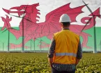 Engineer stood in front of wind turbines and a Welsh flag 