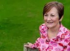 Lady sitting on a bench smiling 